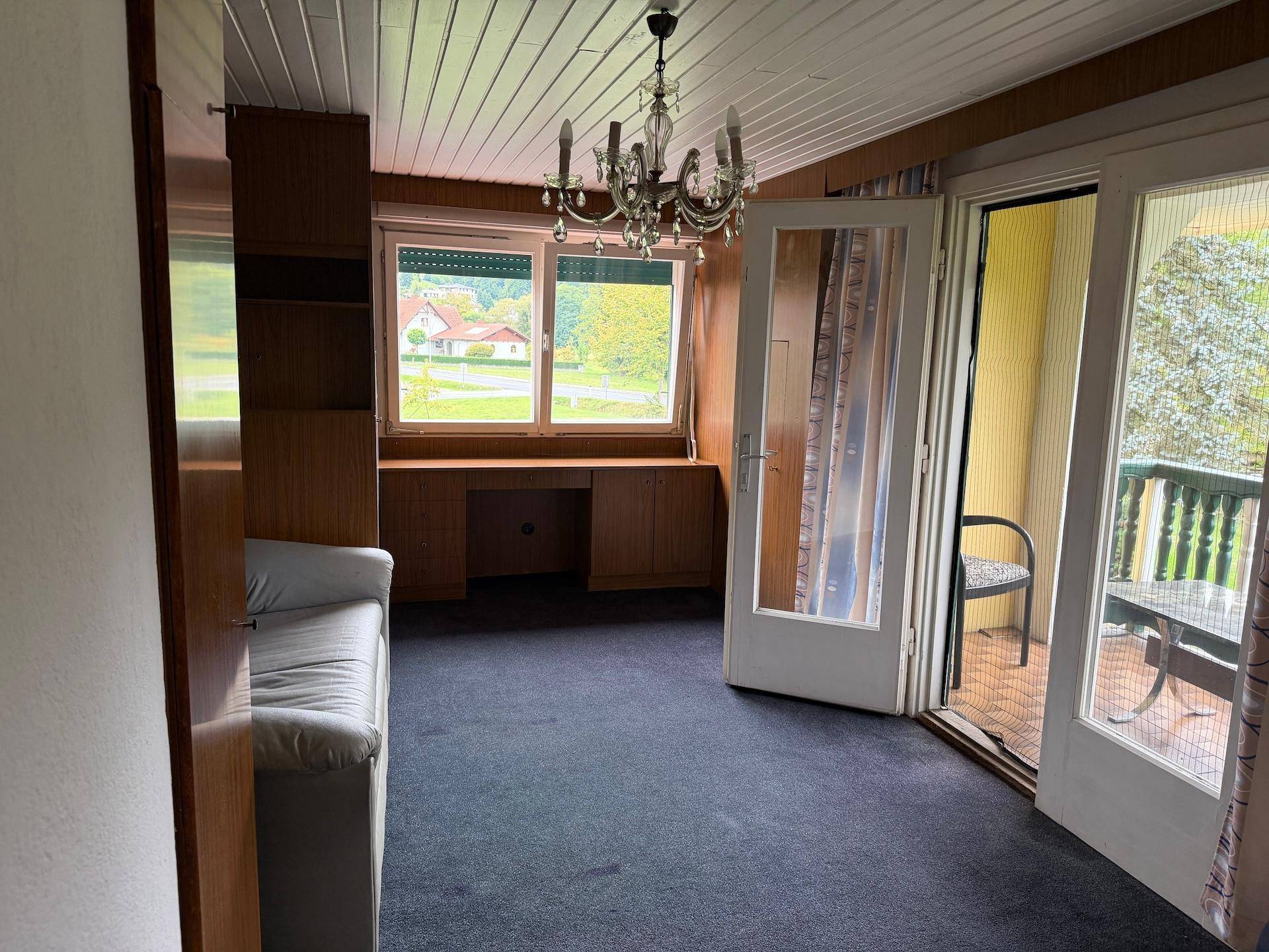 Schlafzimmer mit Balkonzugang, integriertem Schreibtisch und Blick auf die umliegende Landschaft.