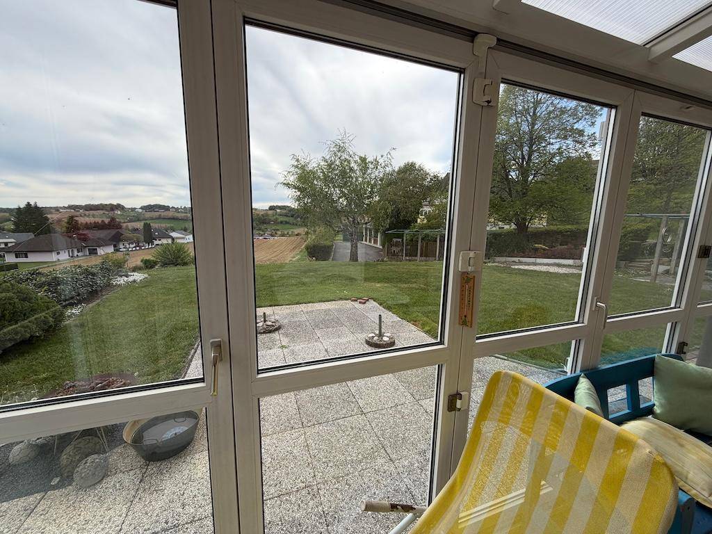 Heller Wintergarten mit großen Fenstern, Blick auf den Garten und die umliegende Landschaft.