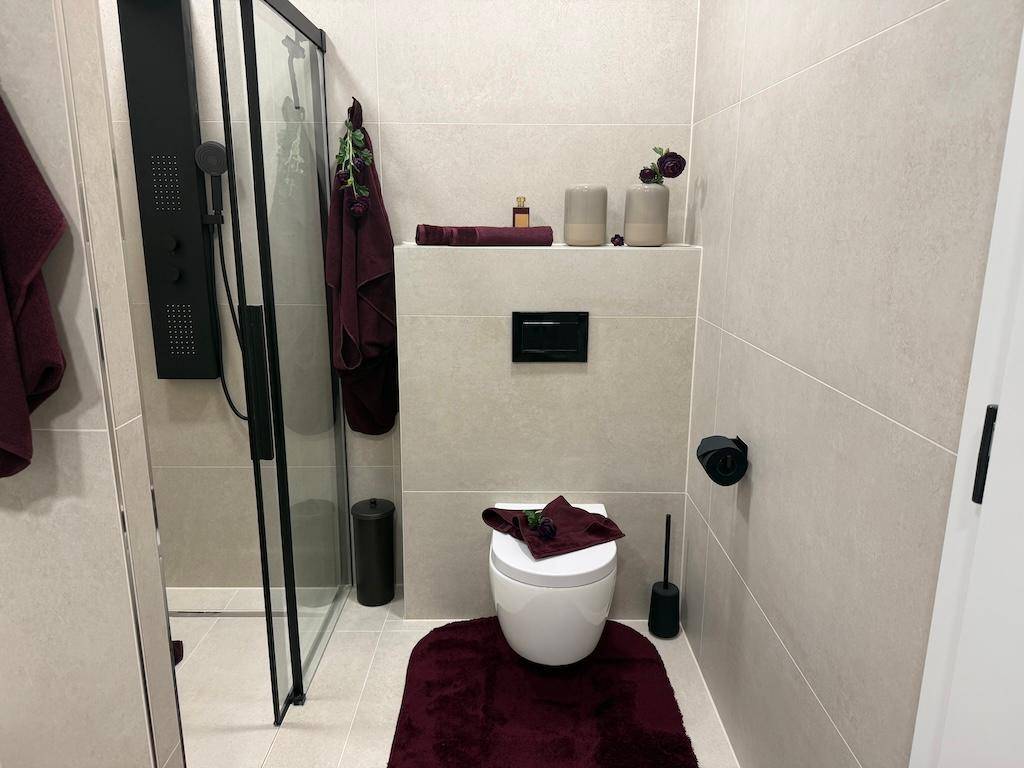 Modernes Badezimmer mit Duschkabine, wandhängendem WC und hellen Fliesen.