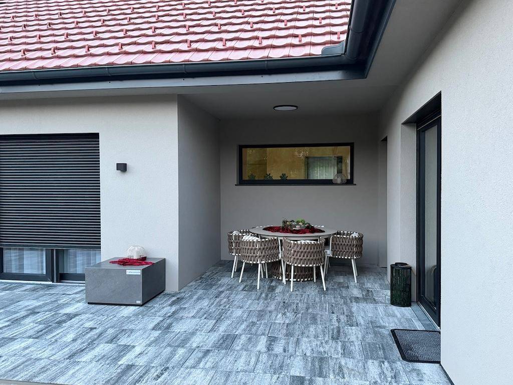 Überdachte Terrasse mit Esstisch und Stühlen, ideal für Mahlzeiten im Freien.
