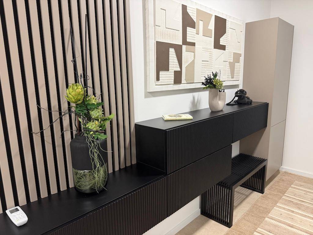 Elegante schwarze Konsole mit moderner Dekoration und strukturiertem Wandbild in einem Flur.