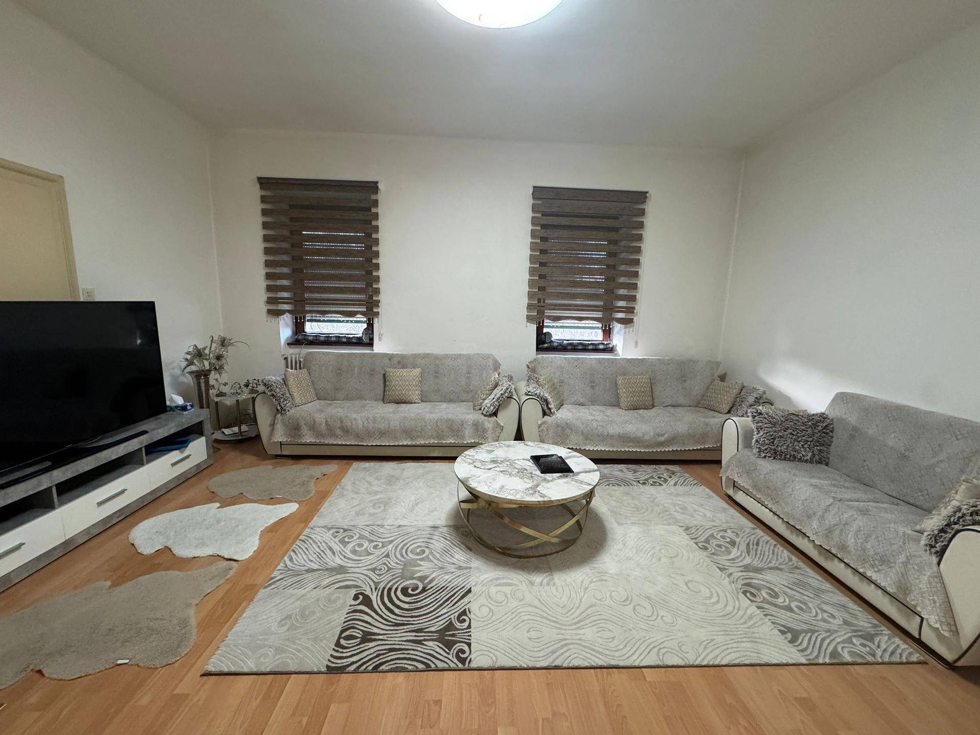 Geräumiges Wohnzimmer mit zwei Sofas, einem großen Teppich und Holzfußboden.