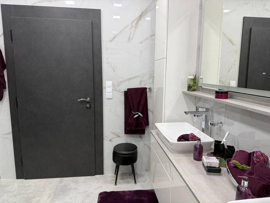 Modernes Badezimmer mit stilvoller Tür, Waschbeckenbereich und einem kleinen Hocker.