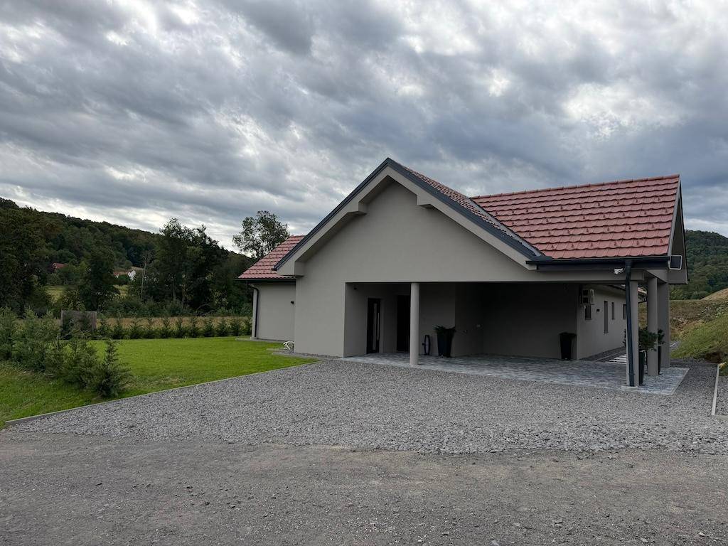 Weitläufige Ansicht des modernen Hauses mit Carport und großem Grundstück in ländlicher Umgebung.