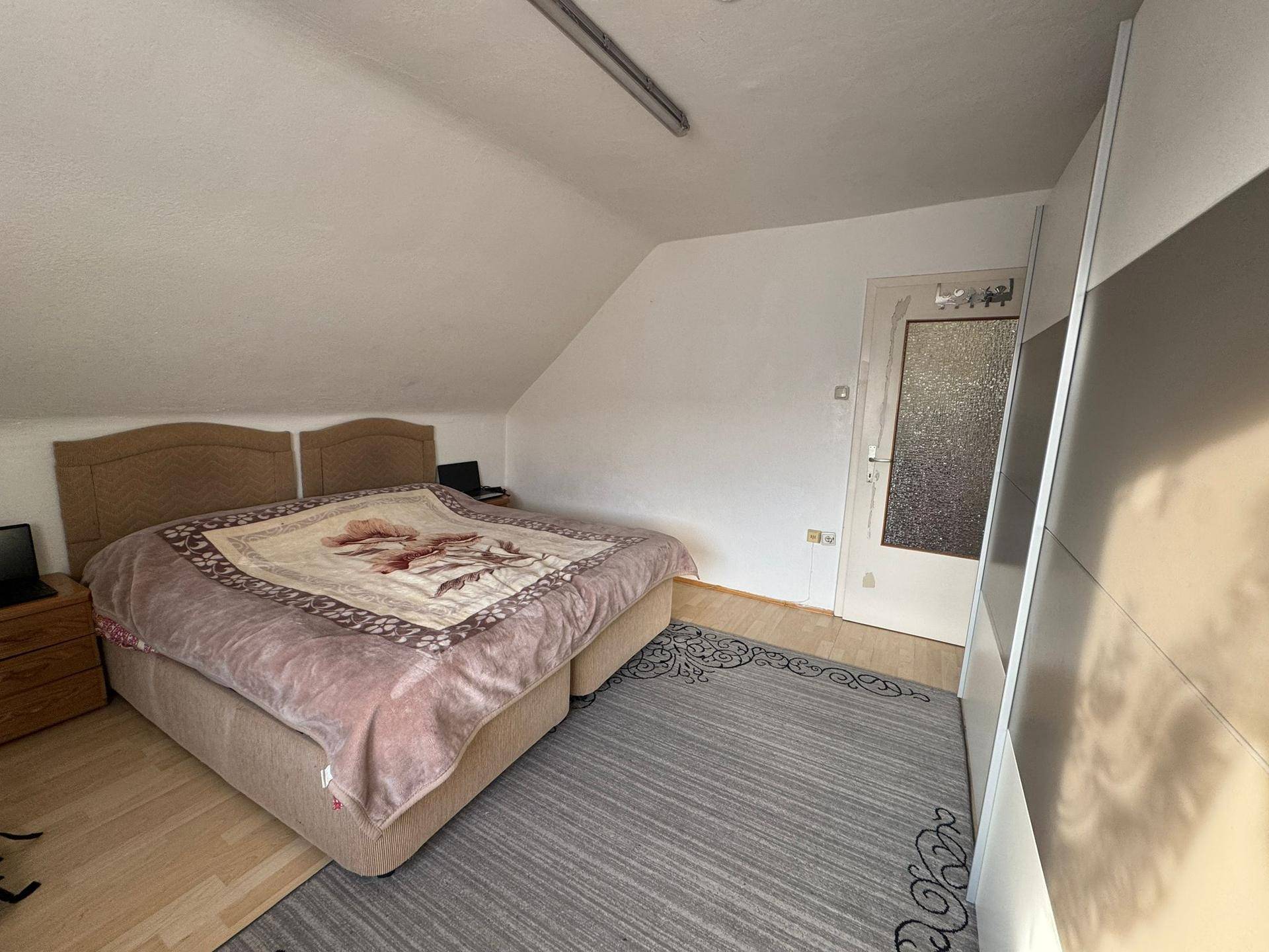 Geräumiges Schlafzimmer im Dachgeschoss mit Doppelbett und großem Schiebetürenschrank.