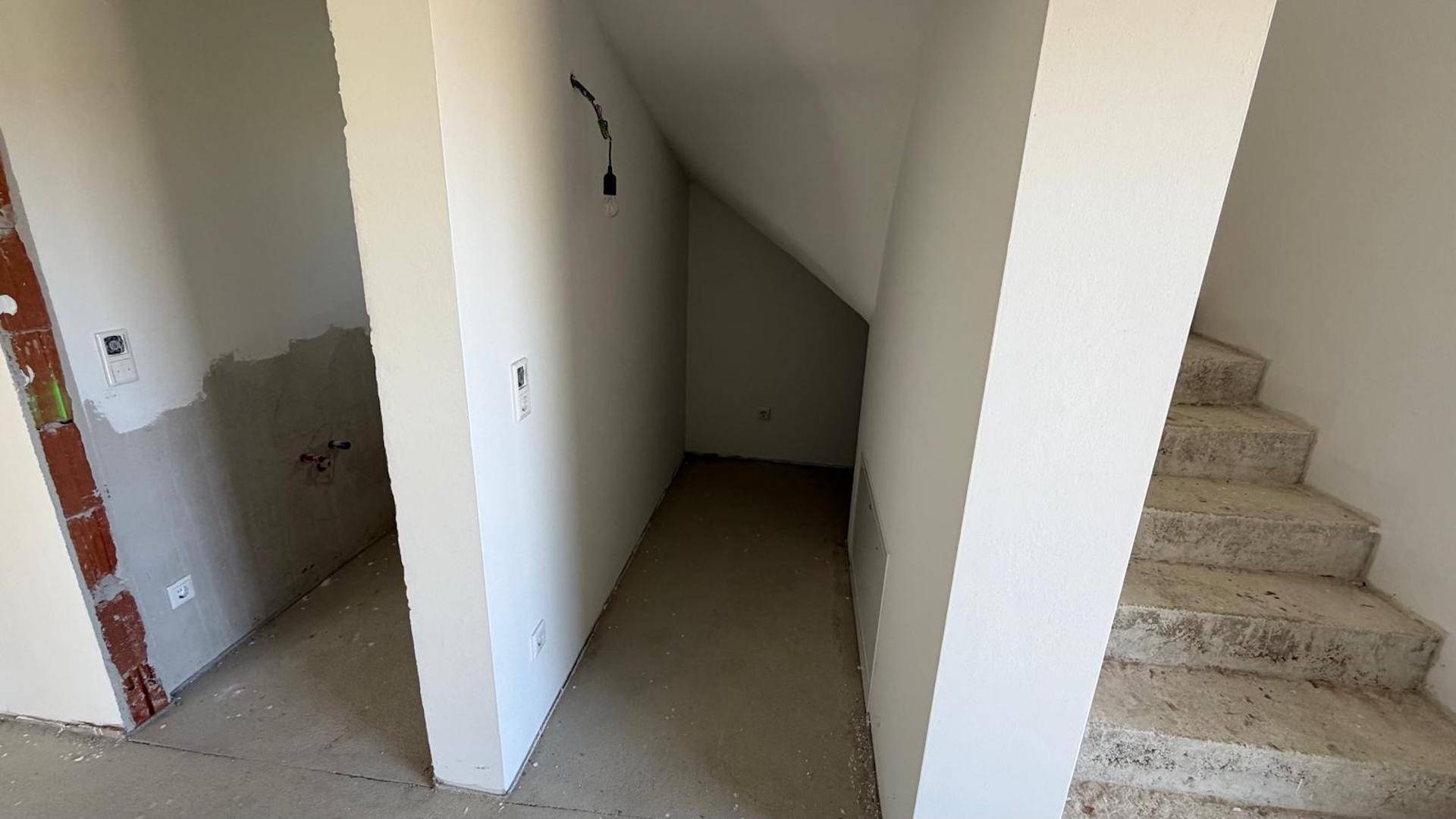 Abstellraum unter der Treppe und angrenzender Bereich im Rohbau, ideal für Lagerung.