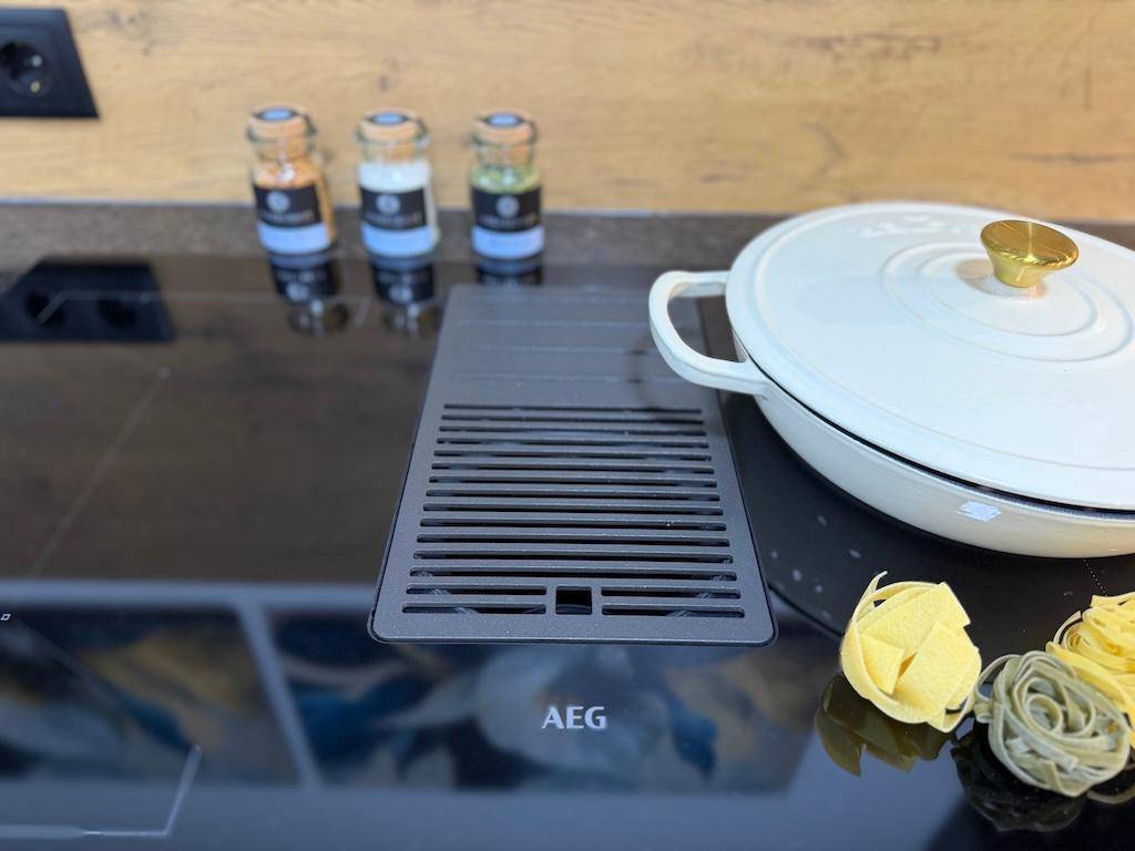 Induktionskochfeld von AEG mit integriertem Dunstabzug und Kochtopf.