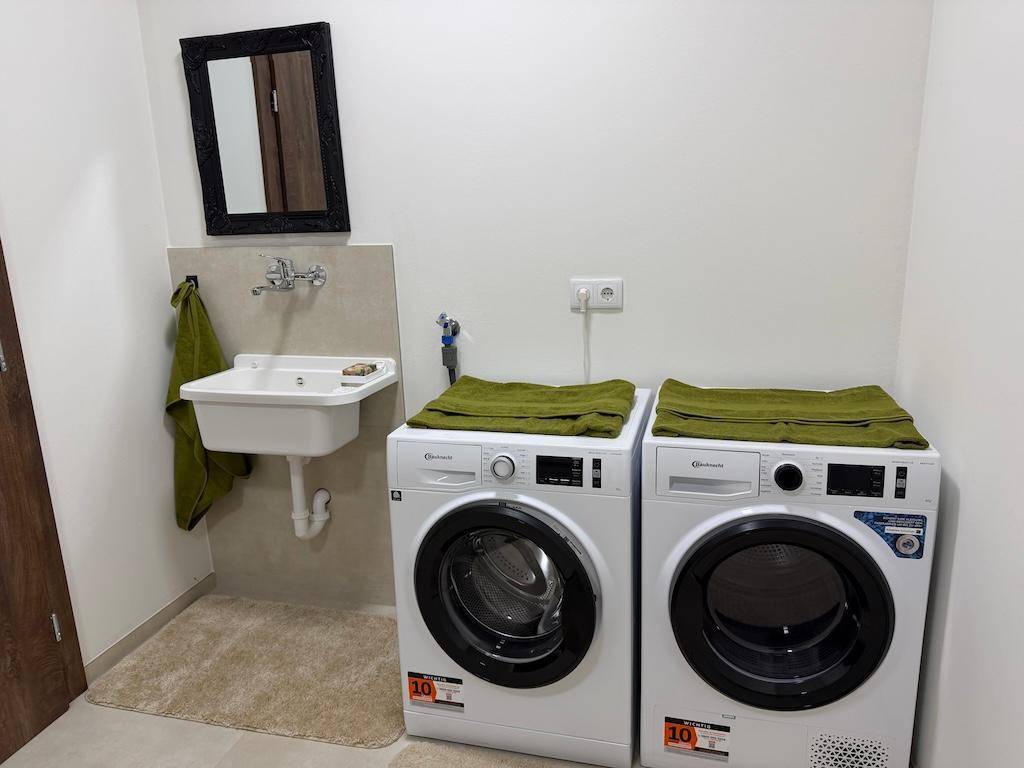 Praktischer Hauswirtschaftsraum mit Waschmaschine, Trockner und kleinem Waschbecken.