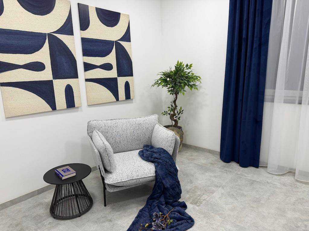 Moderne Sitzecke mit einem Sessel, Beistelltisch und abstrakten Kunstwerken in Blautönen.