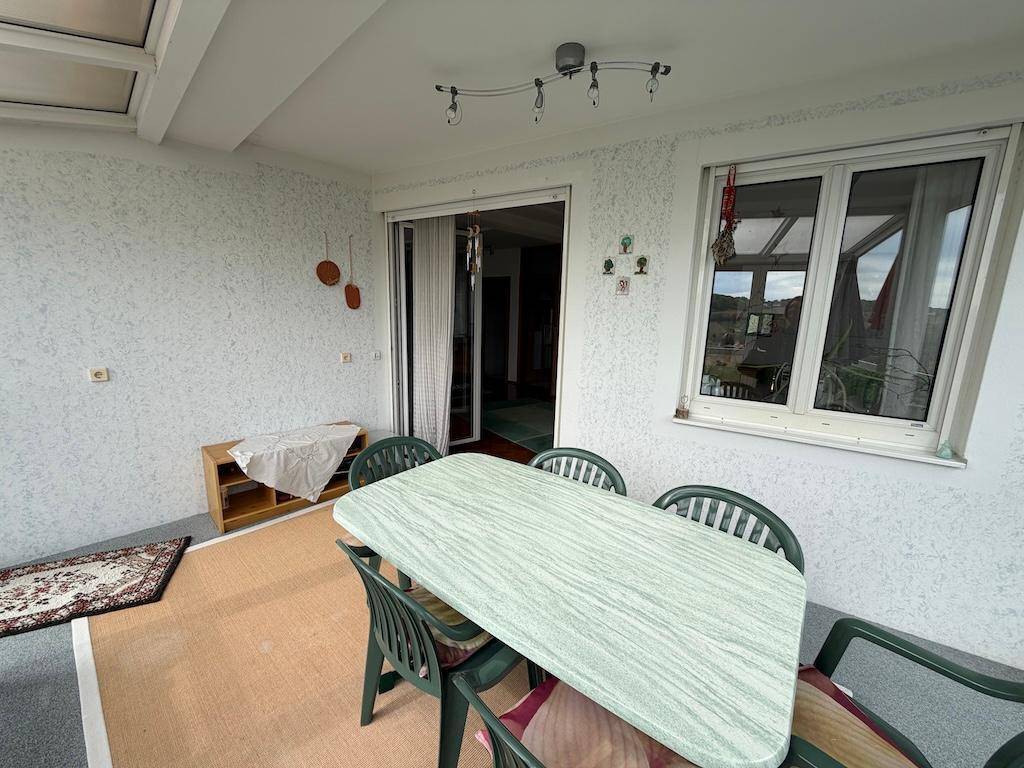 Überdachte Loggia mit Esstisch und Stühlen, ideal für Mahlzeiten im Freien.