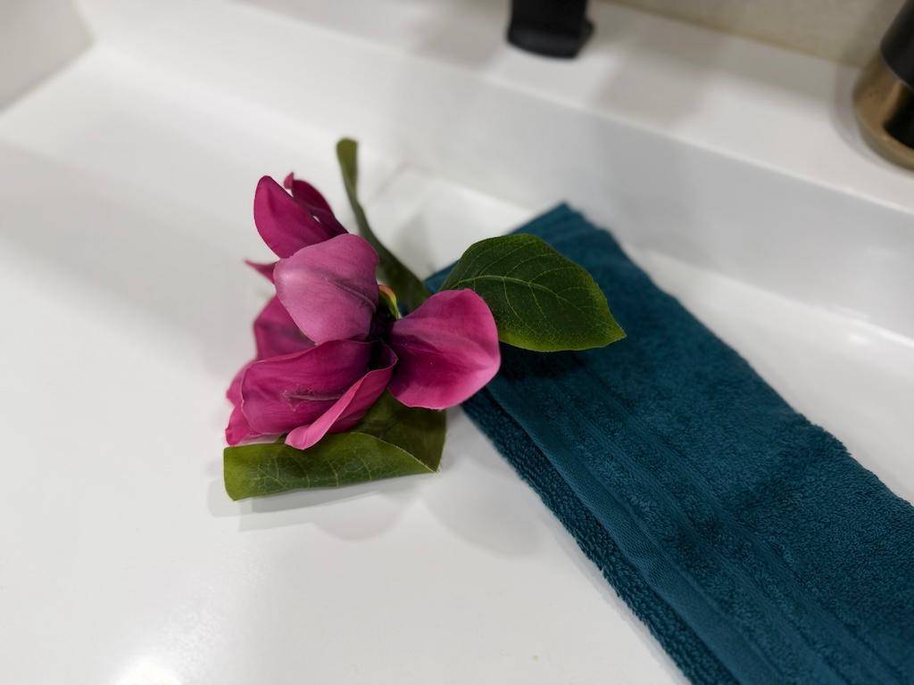 Detailansicht eines türkisfarbenen Handtuchs mit dekorativer Blume auf einem Waschbecken.