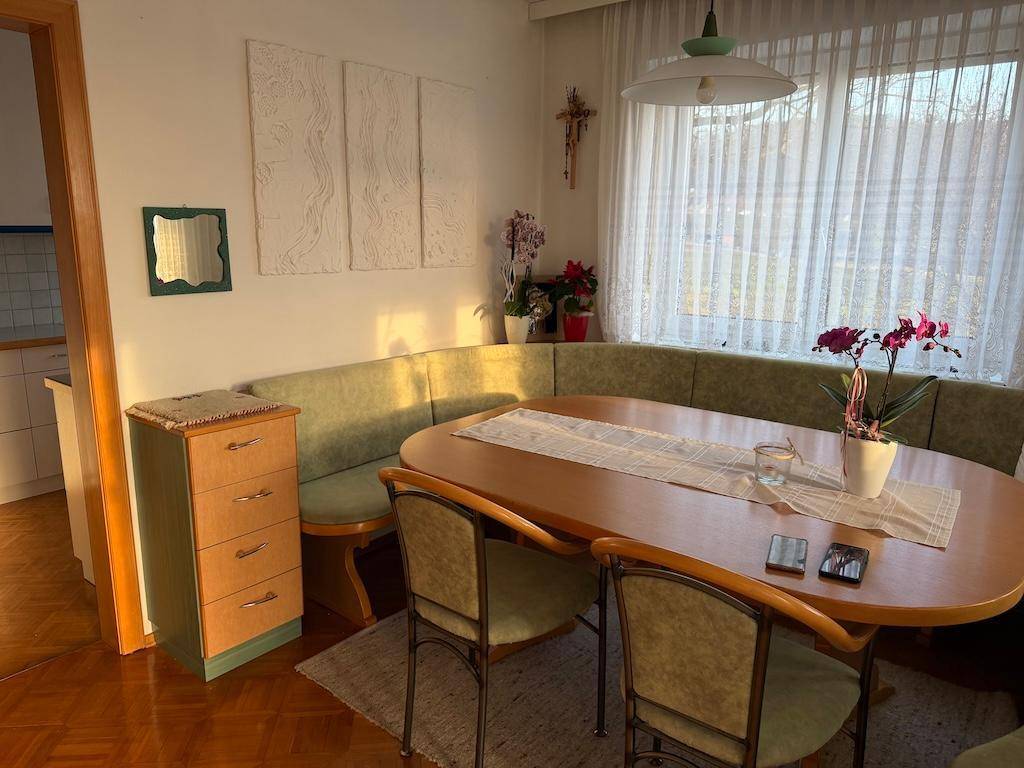 Gemütlicher Essbereich mit Eckbank, Holztisch und Blick durch das Fenster.