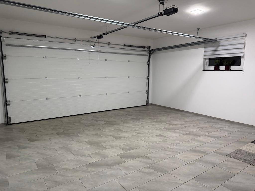 Saubere und geräumige Garage mit einem großen Sektionaltor und gefliestem Boden.