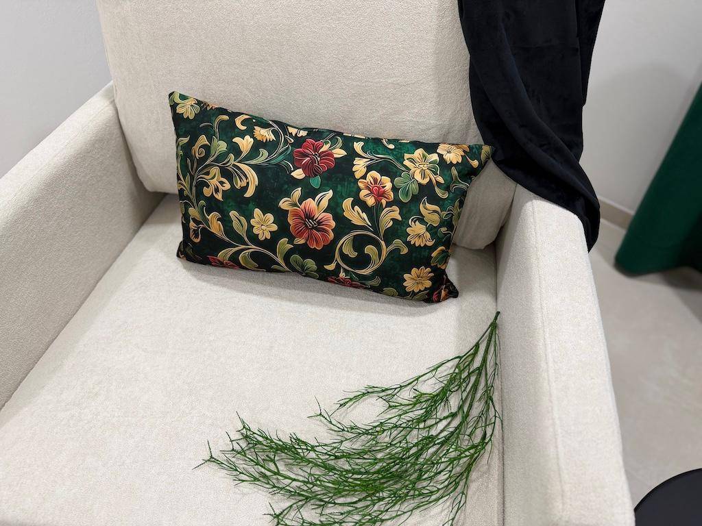 Detailansicht eines floral gemusterten Kissens auf einem beigen Sessel mit grüner Dekoration.