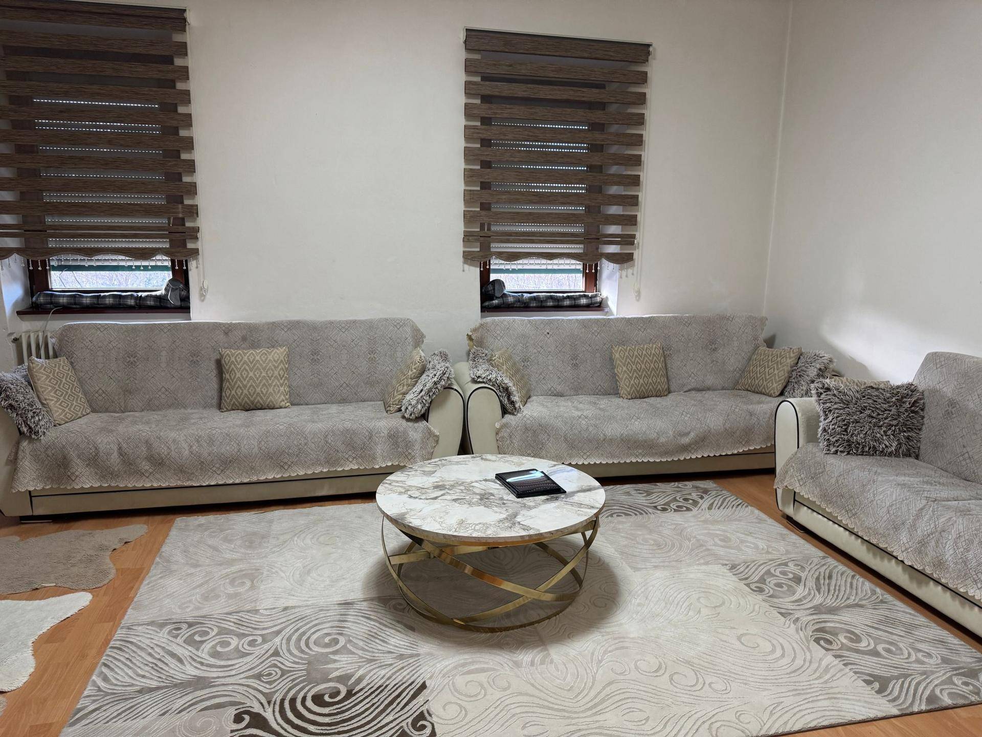 Helles Wohnzimmer mit zwei Sofas, einem gemusterten Teppich und einem runden Couchtisch.