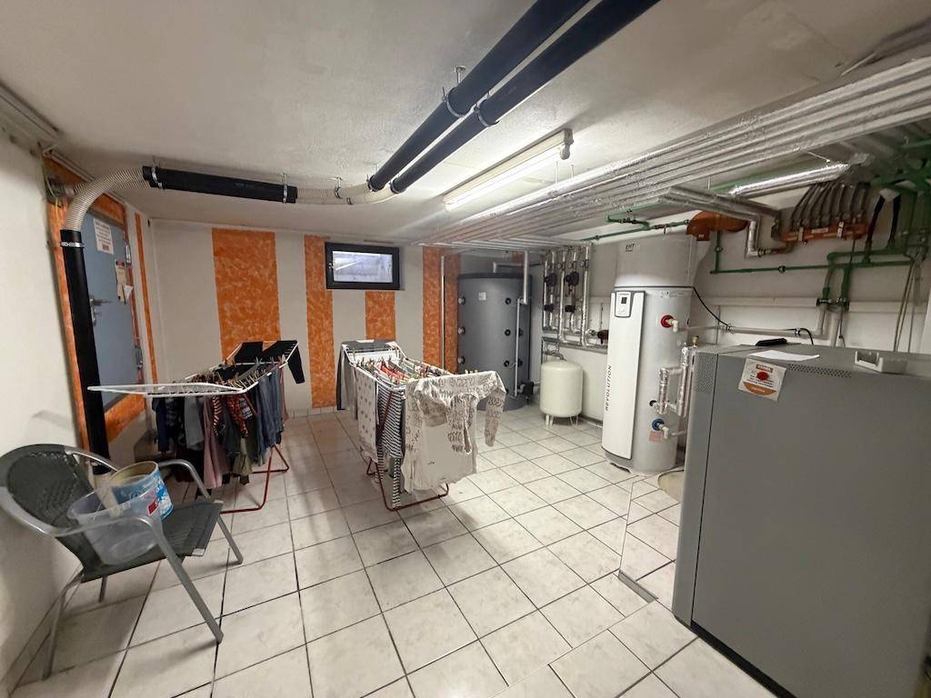 Geräumiger Hauswirtschaftsraum mit Heizungsanlagen, Rohren und Wäscheständern.