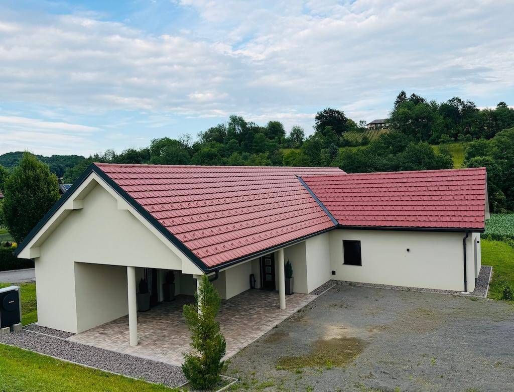 Vogelperspektive eines modernen Hauses mit großem gepflasterten Vorplatz und Carport.