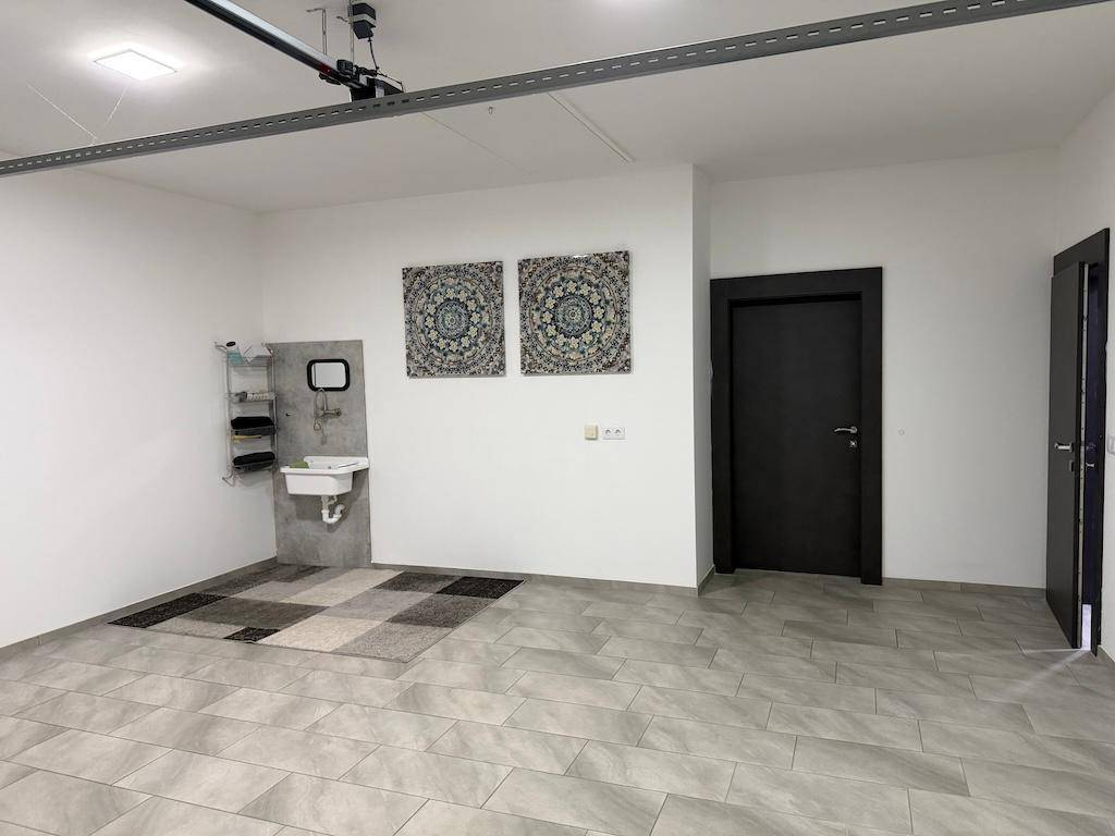 Helle Garage mit viel Platz, gefliestem Boden und einem praktischen Waschbeckenbereich.