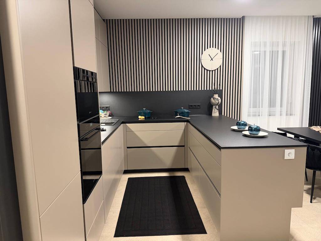 Elegante U-förmige Küche mit beigen Schränken, dunkler Arbeitsplatte und integriertem Backofen.