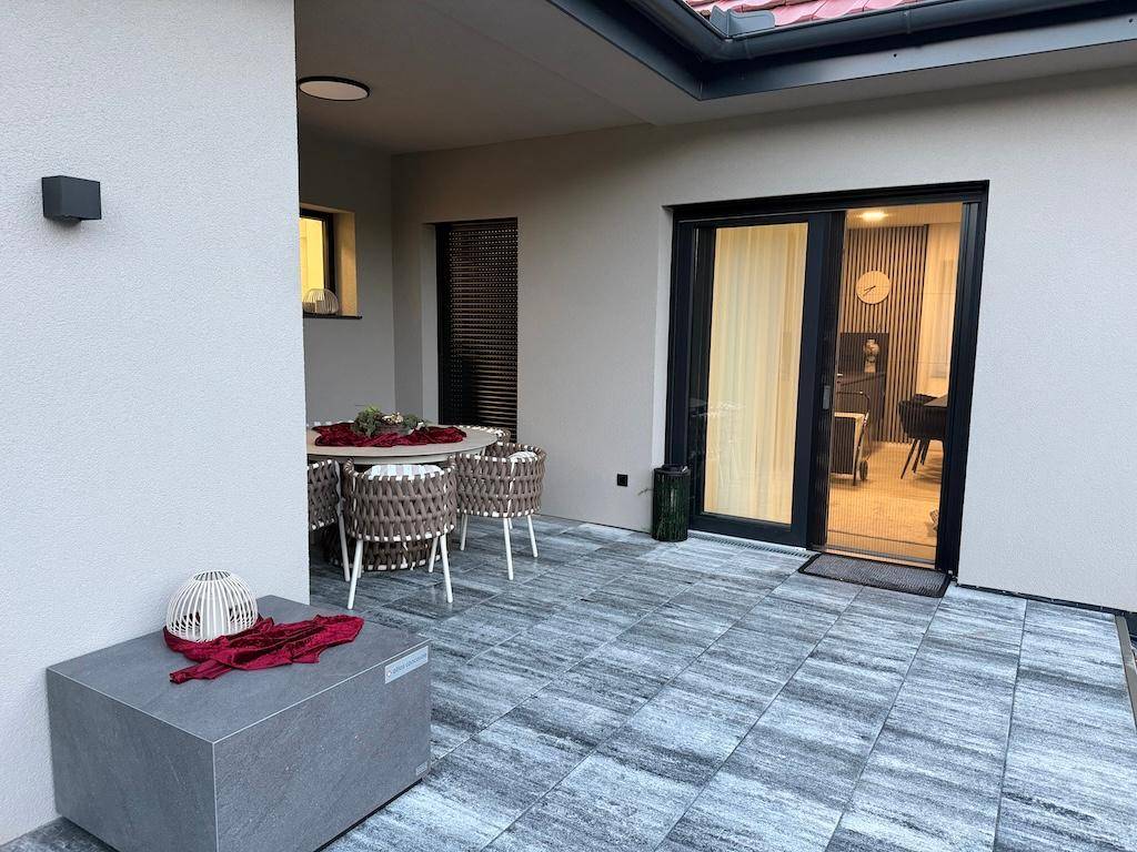 Gemütliche Terrasse mit modernen Fliesen, Esstisch und Zugang zum Innenbereich des Hauses.