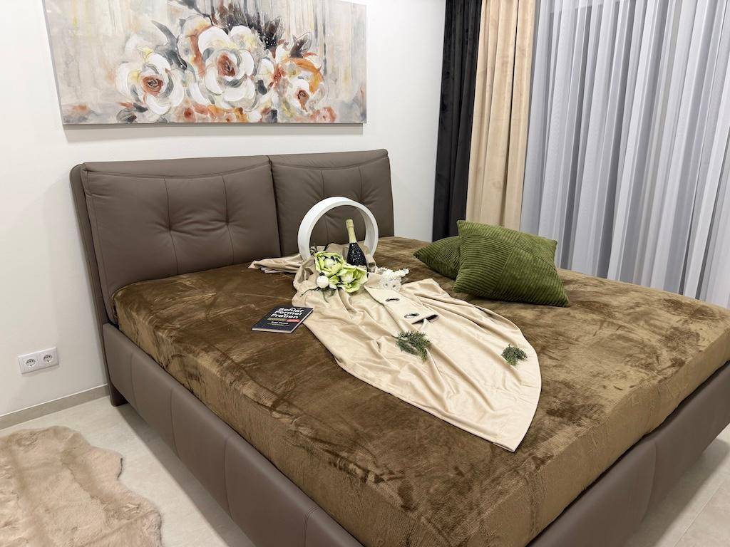 Gemütliches Schlafzimmer mit großem Doppelbett, Kunstwerk und Vorhängen am Fenster.