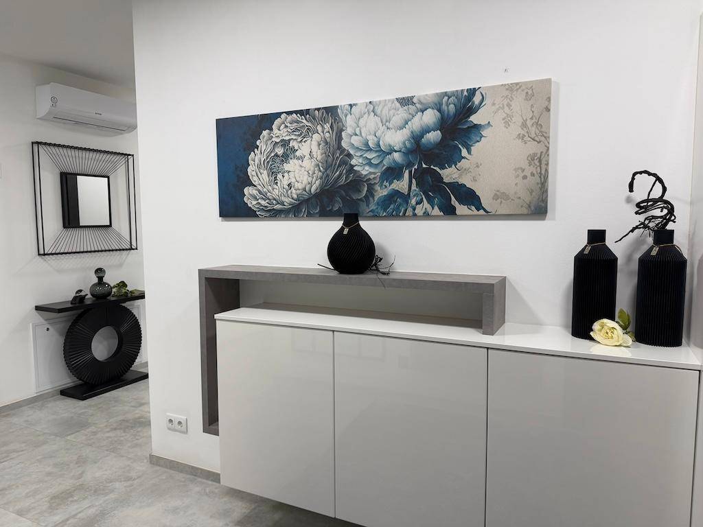 Stilvolle Einrichtung im Flur mit großem Kunstwerk, Sideboard und modernen Dekorationsartikeln.
