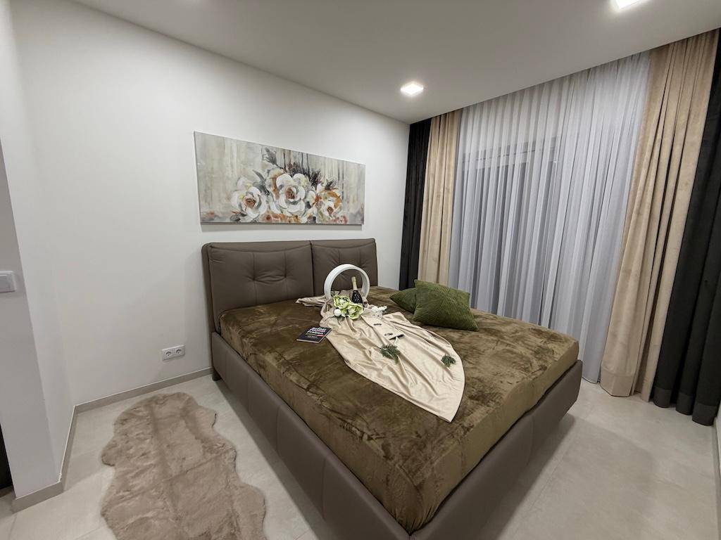 Modernes Schlafzimmer mit großem Bett, Kunstwerk und Vorhängen, die für Privatsphäre sorgen.