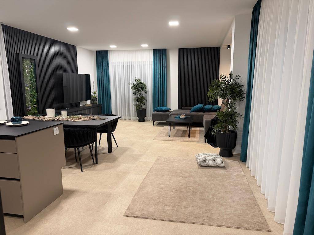 Weitläufiger offener Wohnbereich mit moderner Einrichtung, Teppich und dekorativen Pflanzen.
