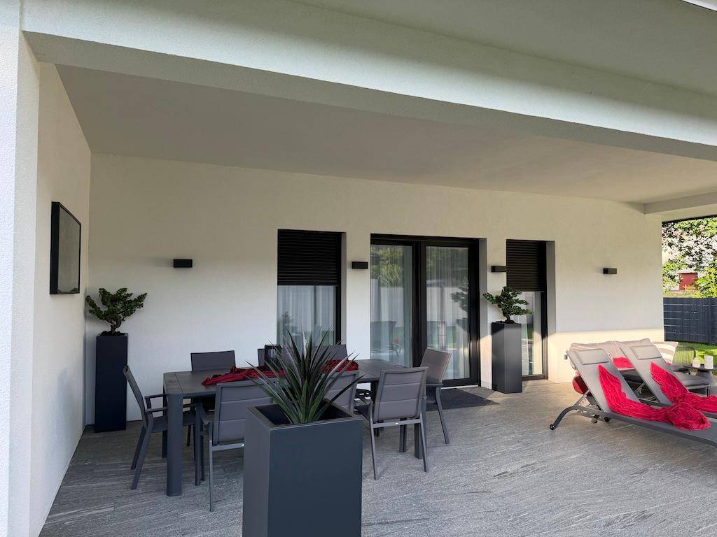 Überdachte Terrasse mit Essbereich und Liegestühlen, ideal für entspannte Stunden im Freien.
