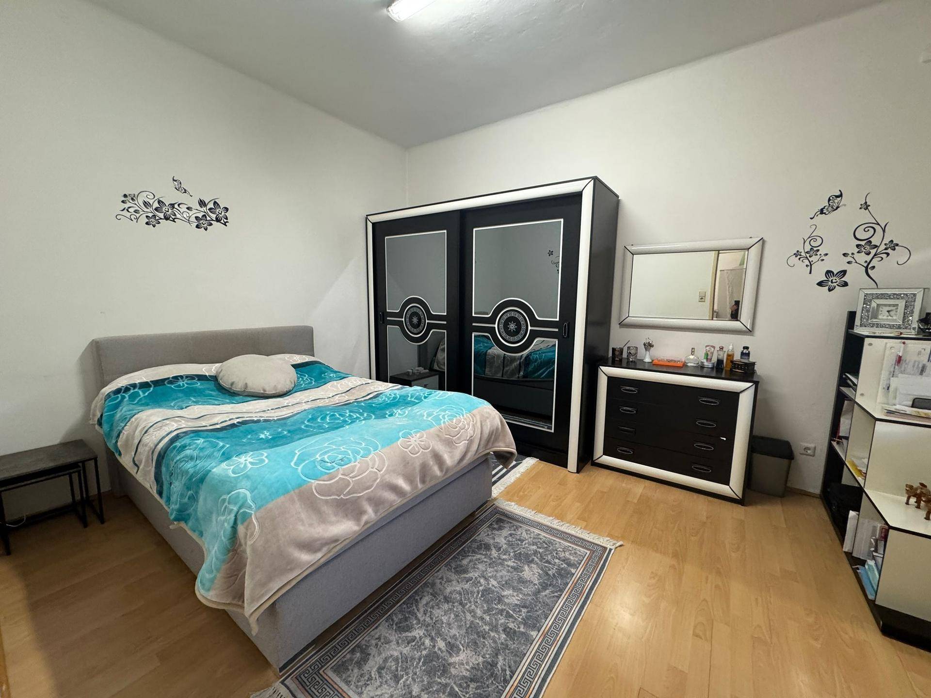 Schlafzimmer mit Doppelbett, modernem Kleiderschrank und Kommode auf Holzfußboden.