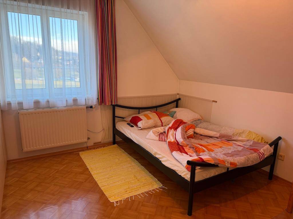 Helles Schlafzimmer mit Einzelbett, Holzboden und schräger Decke im Dachgeschoss.