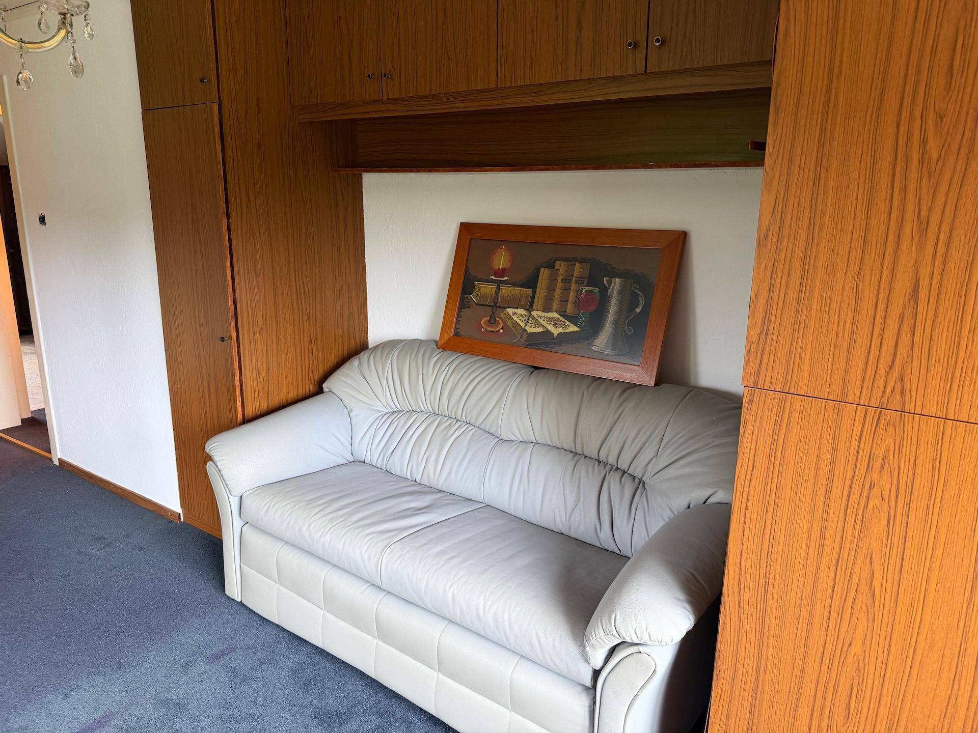 Wohnbereich mit bequemer Couch, integrierten Holzschränken und einem dekorativen Wandbild.