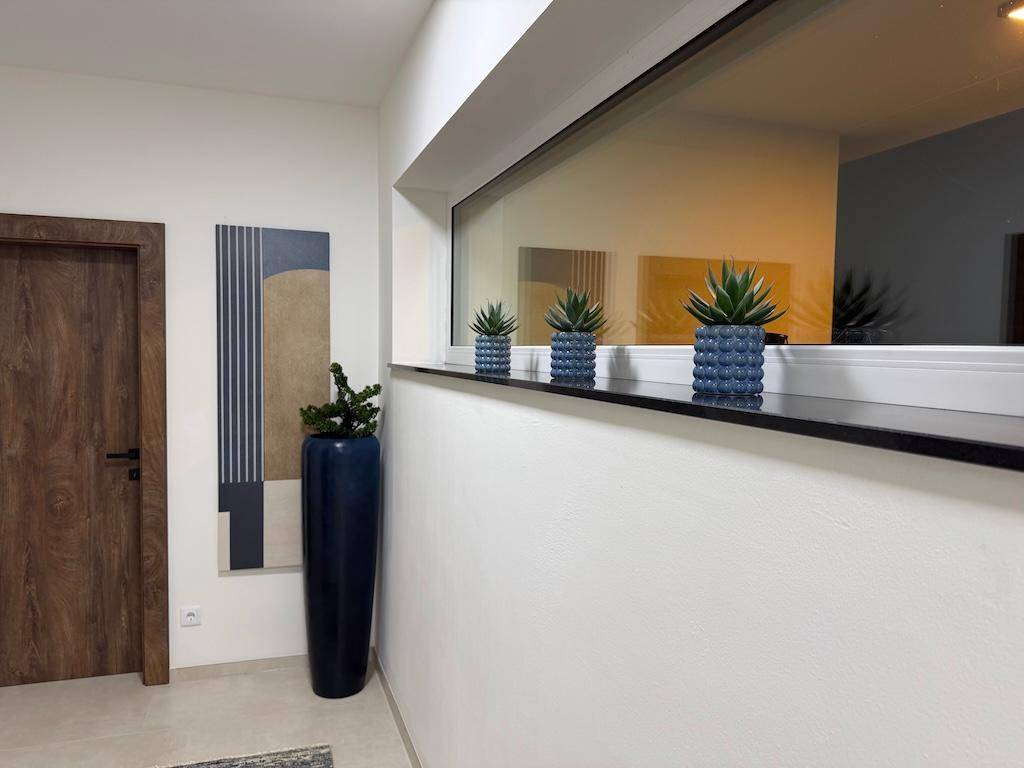 Heller Flur mit einem breiten Fenster, das mit blauen Pflanztöpfen und Sukkulenten dekoriert ist.