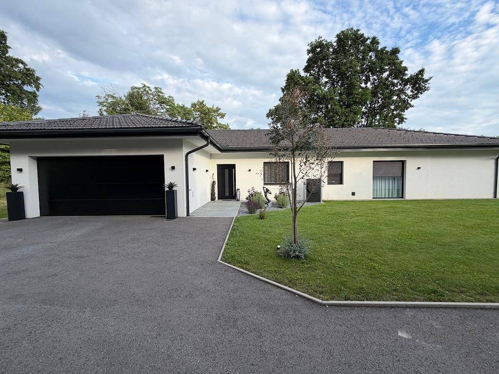 Attraktives Einfamilienhaus mit integrierter Garage, gepflegtem Rasen und moderner Architektur.