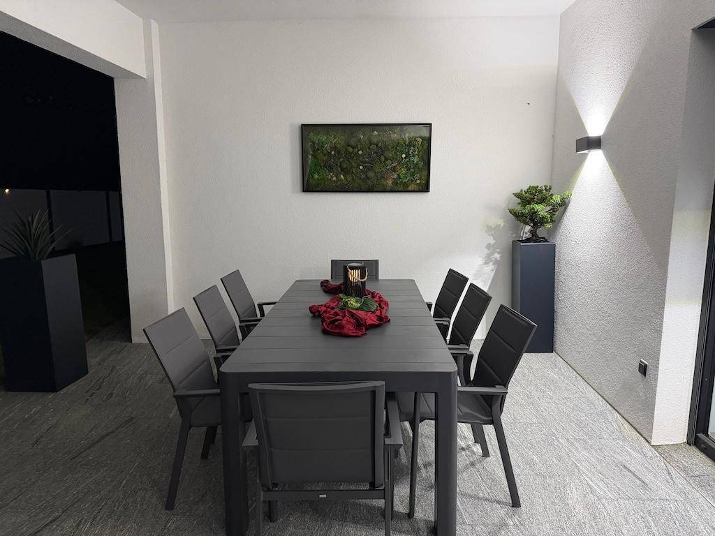 Überdachter Essbereich auf der Terrasse mit großem Tisch und Stühlen, ideal für gesellige Abende.