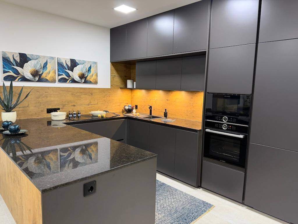 Moderne Küche mit dunklen Schränken, Holzrückwand und integrierten Elektrogeräten.