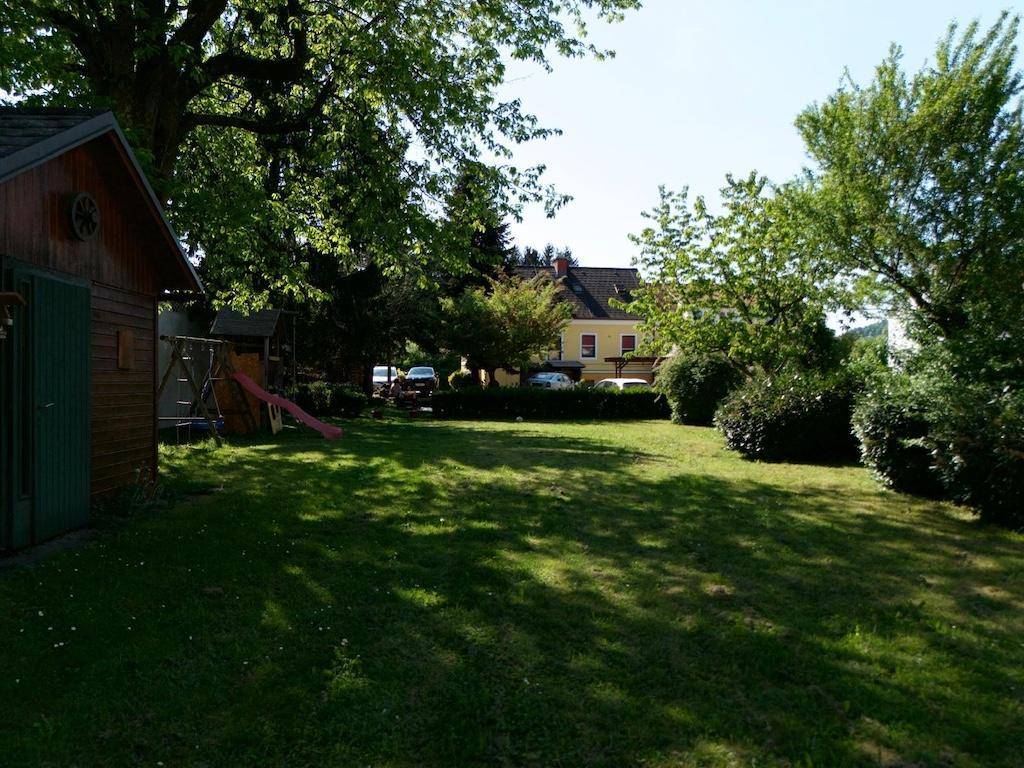 Großer grüner Garten mit Rasen, Bäumen, Schuppen und Blick auf das Haus.