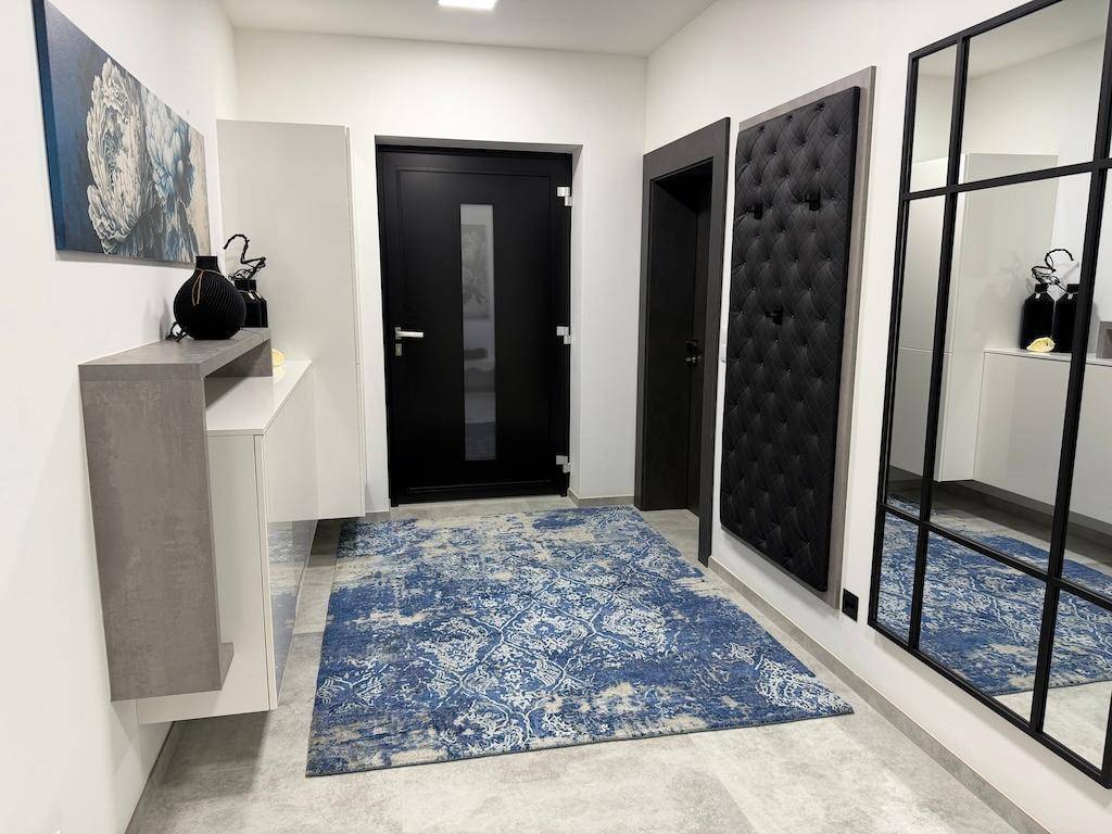 Geräumiger Flur mit blauem Teppich, großem Spiegel und modernem Sideboard.