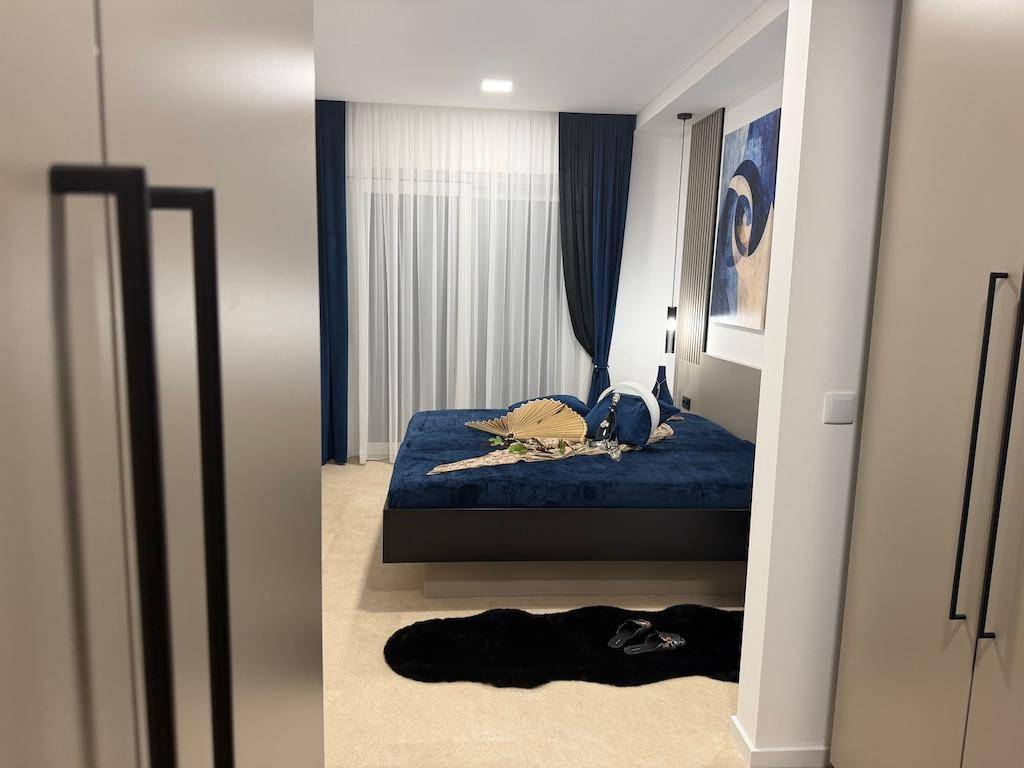 Modernes Schlafzimmer mit großem Bett, blauer Bettwäsche und stilvollen Wandbildern.