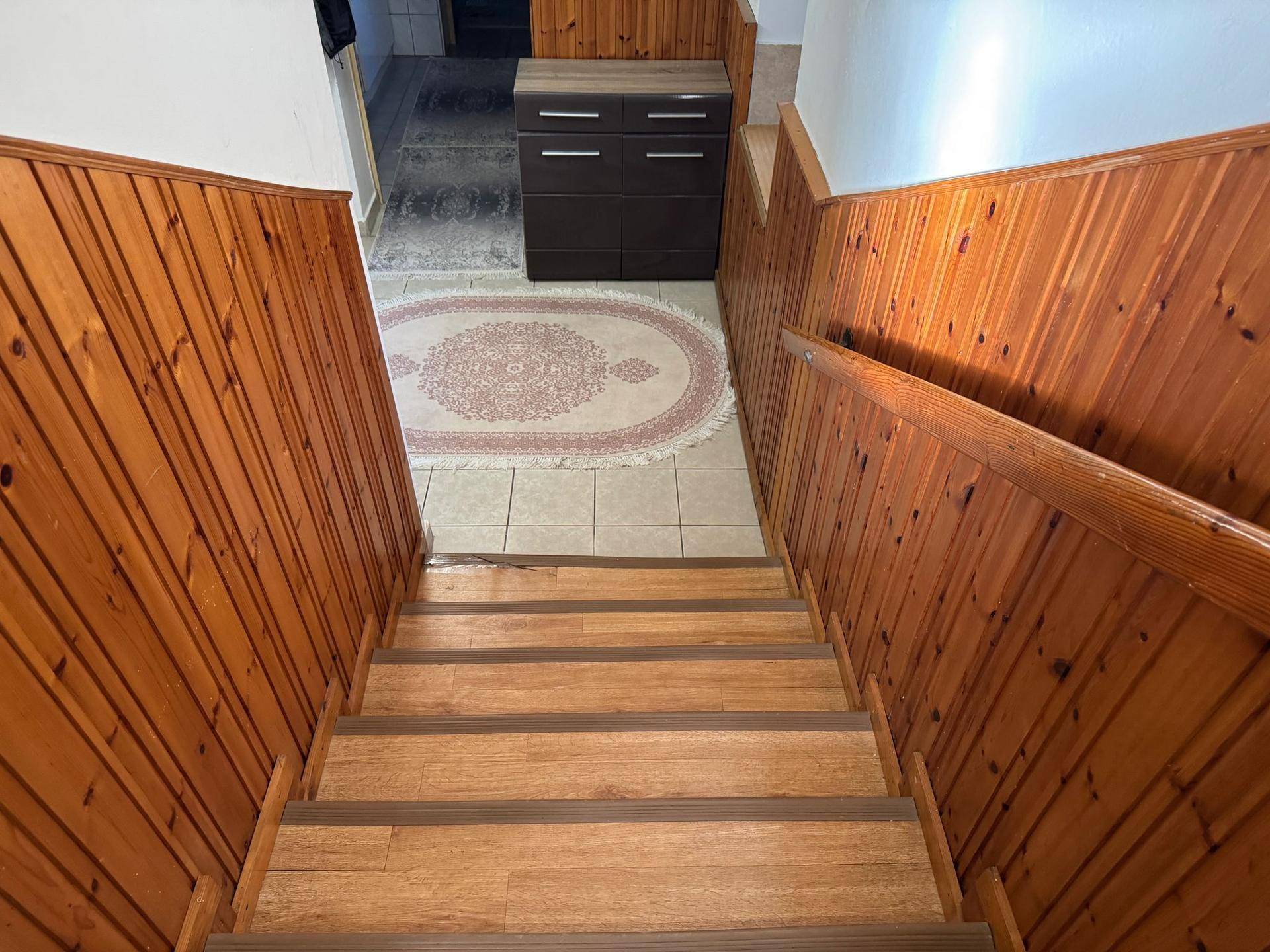 Treppenhaus mit Holzvertäfelung, Holztreppe und einem Teppich im unteren Bereich.
