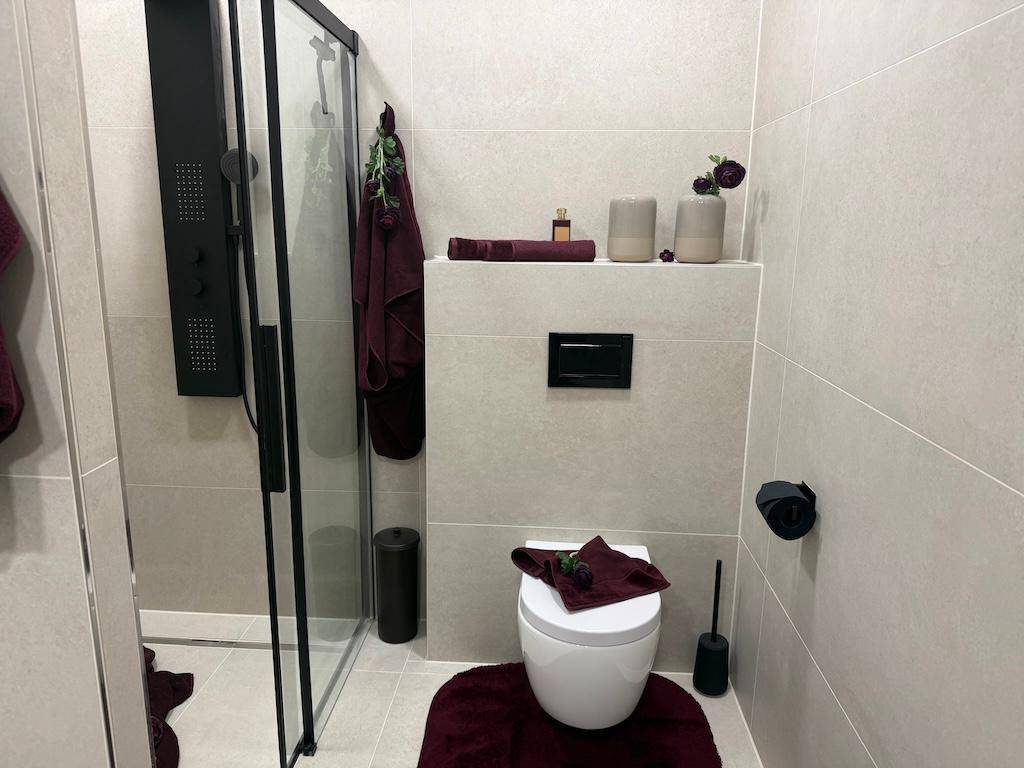 Modernes Badezimmer mit Duschkabine, wandhängendem WC und hellen Fliesen.