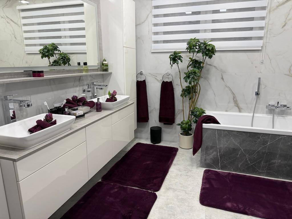 Geräumiges Badezimmer mit Doppelwaschbecken, Badewanne und großem Fenster für natürliches Licht.