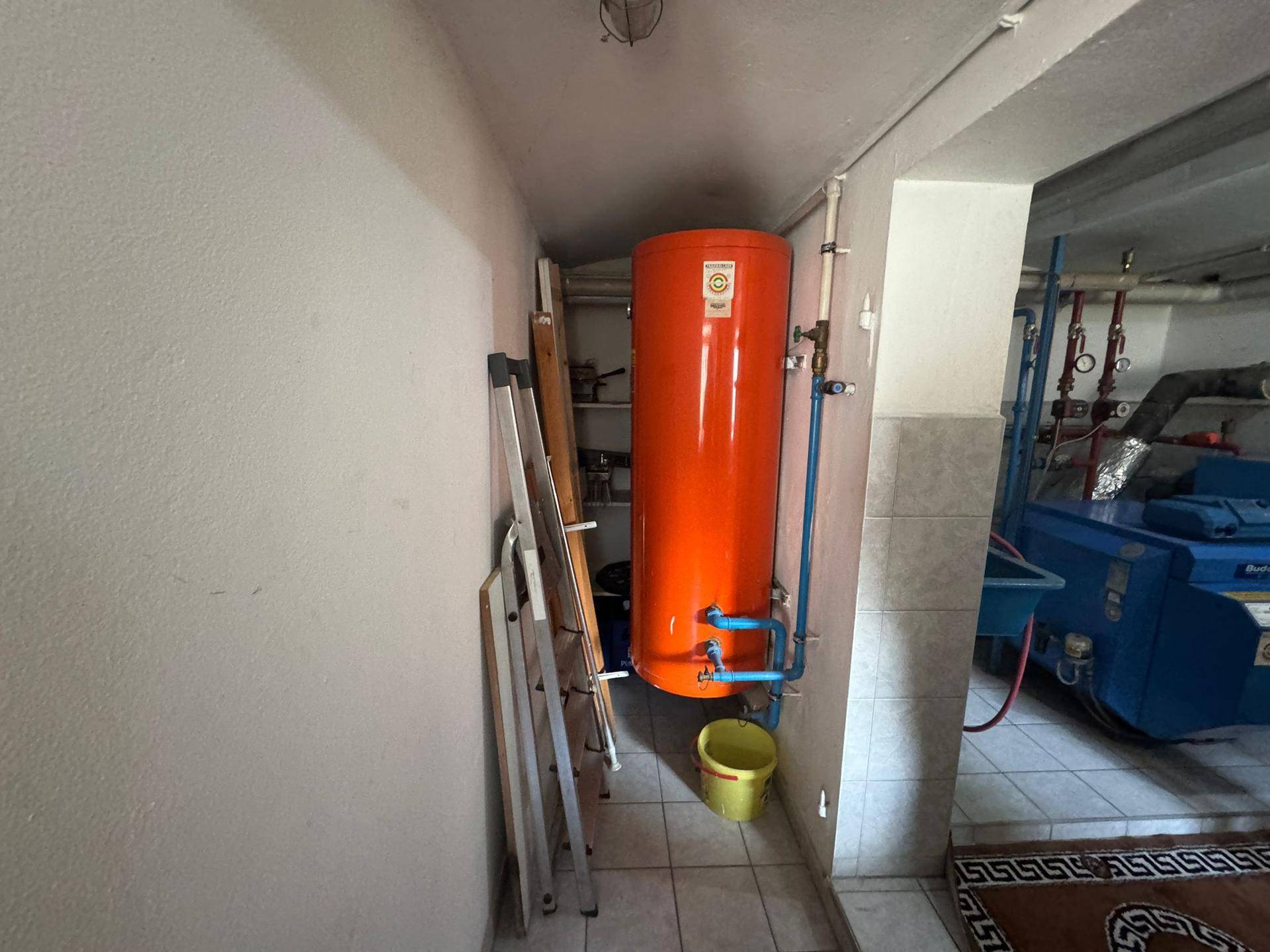 Kellerraum mit Warmwasserspeicher und Leitungen, ideal für Haustechnik.