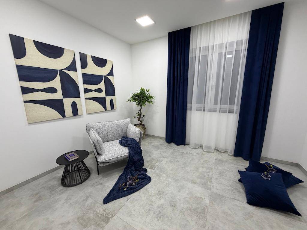 Helle Sitzecke mit einem bequemen Sessel, kleinem Tisch und blauen Kunstwerken an der Wand.