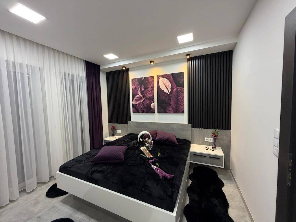 Helles Schlafzimmer mit modernem Bett, stilvollen Wandpaneelen und großen Fenstern für viel Tageslicht.