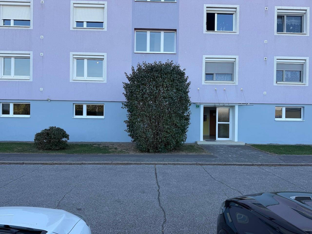 Fassade eines Mehrfamilienhauses mit blauer und hellblauer Farbgebung und Rollläden.