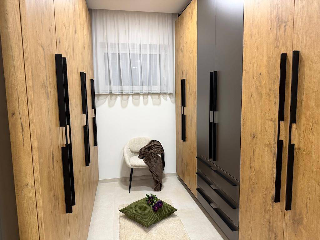 Geräumiger begehbarer Kleiderschrank mit Holzschränken und Fenster für natürliches Licht.