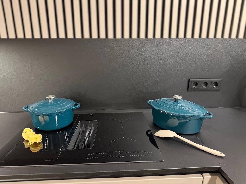 Detailansicht des modernen Induktionskochfelds mit integriertem Dunstabzug und Kochtöpfen.