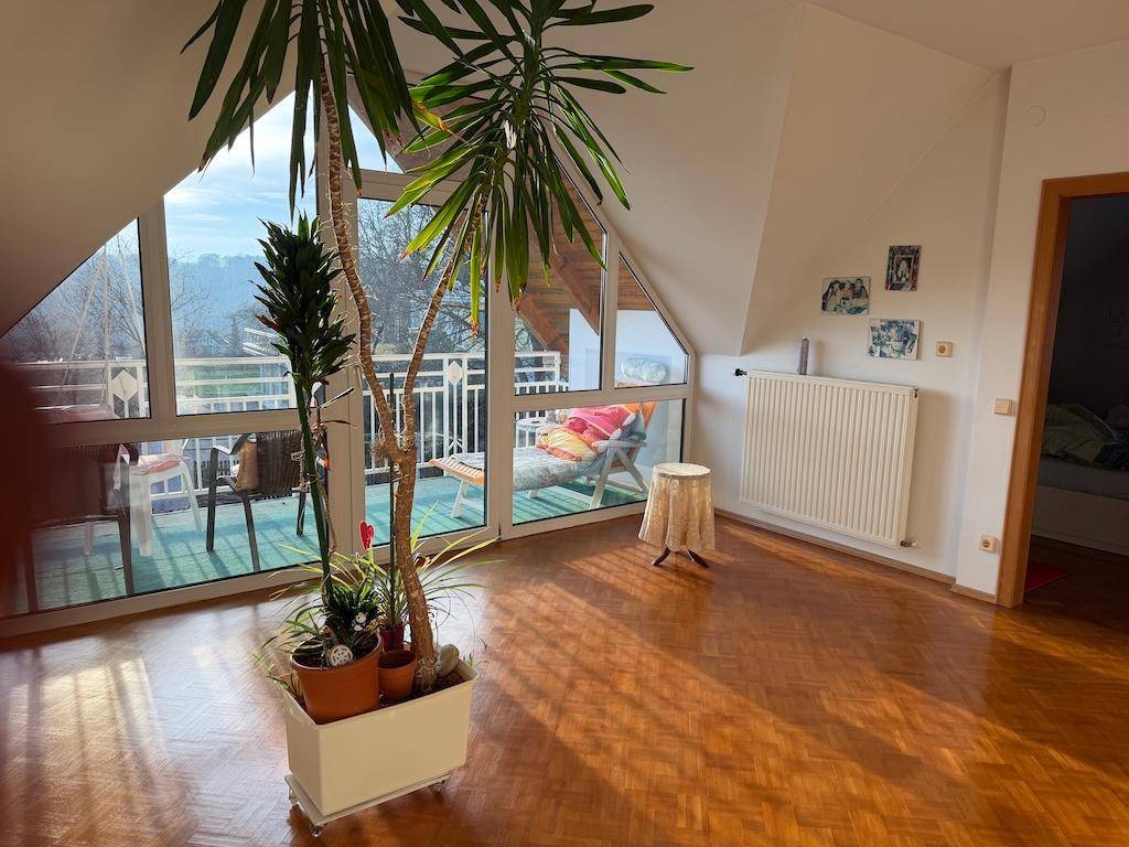 Helles Wohnzimmer im Dachgeschoss mit großen Fenstern und Panoramablick auf die Landschaft.