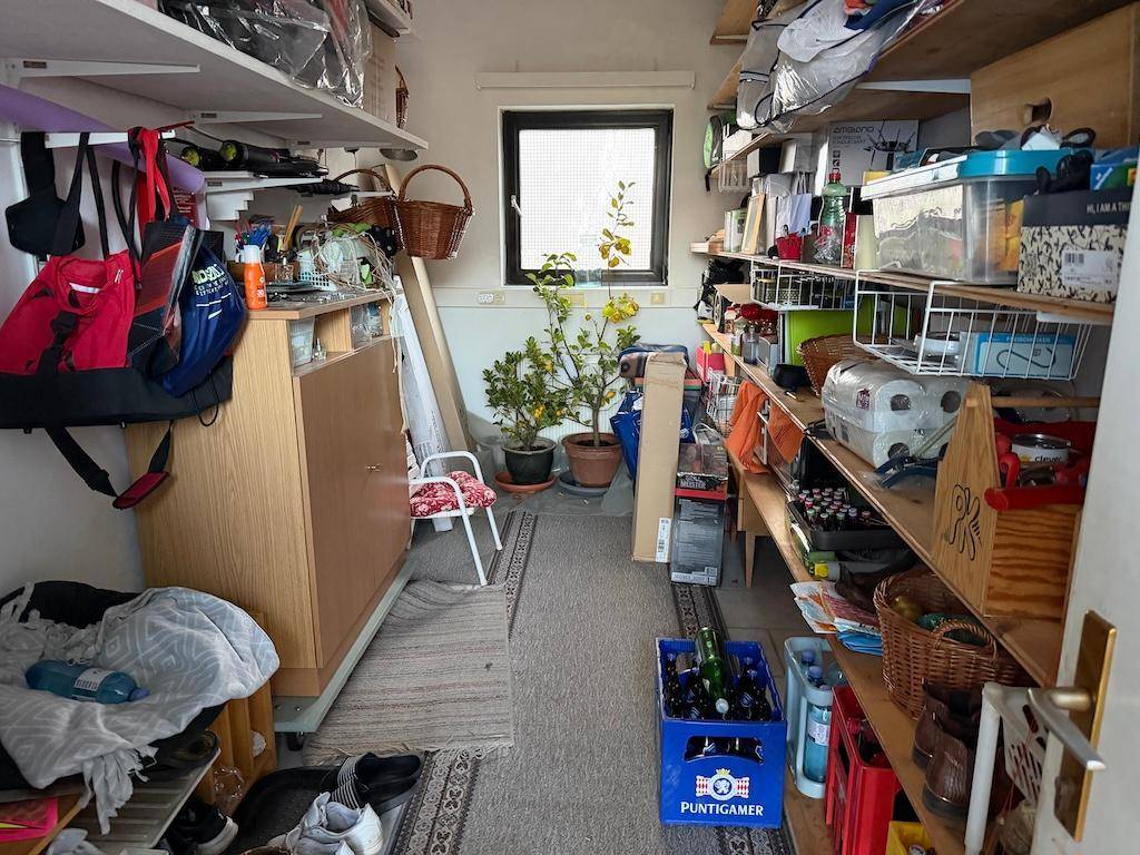 Überfüllter Abstellraum mit Regalen, Kisten und einem kleinen Fenster, ideal für Lagerzwecke.
